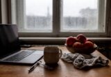 Kuchenny stół w mieszkaniu w kamienicy jesienną porą, kubek herbaty i zamknięty laptop