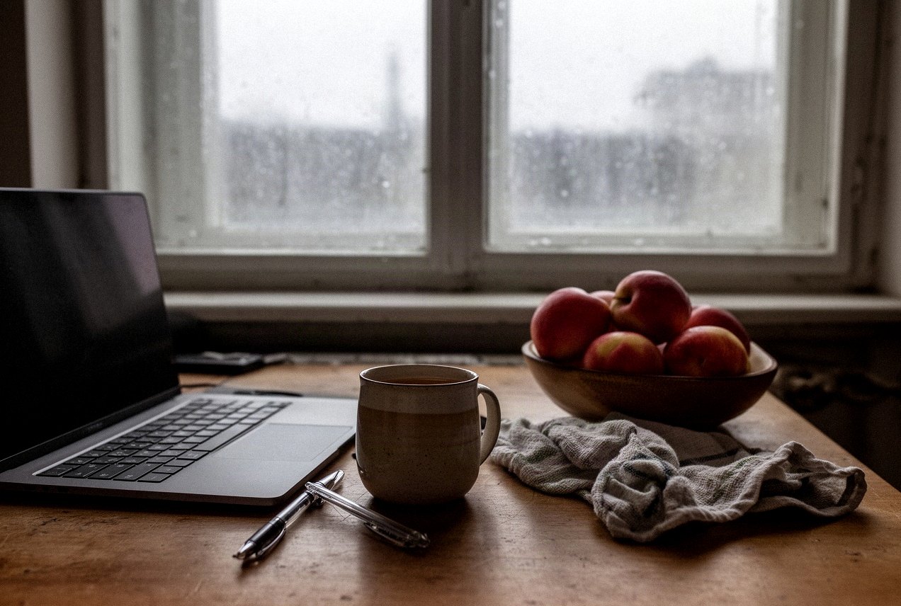 Kuchenny stół w mieszkaniu w kamienicy jesienną porą, kubek herbaty i zamknięty laptop
